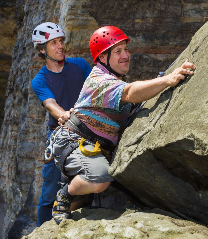 Ein junger Mann mit Down Syndrom klettert auf einem Felsen in der Sächsischen Schweiz 